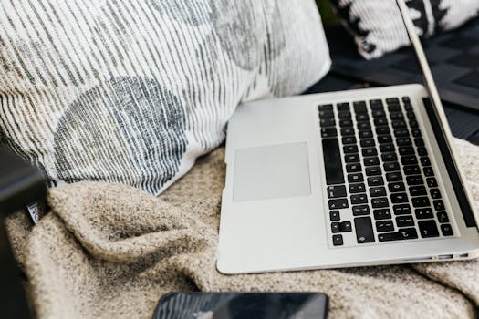 A comfortable setup with a laptop, smartphone, and cozy blankets in an indoor setting.