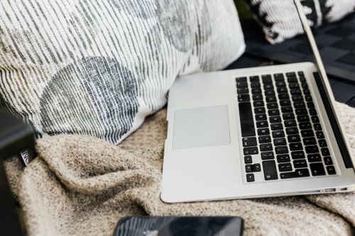 Free A comfortable setup with a laptop, smartphone, and cozy blankets in an indoor setting. Stock Photo