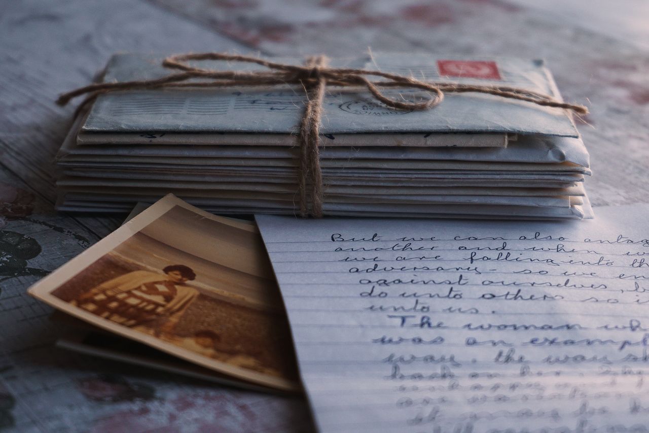 Close-up of vintage letters tied together with a twine, accompanied by an old photograph and handwritten note.