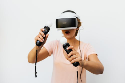 A Woman Wearing a Virtual Reality Headset while Holding Controllers