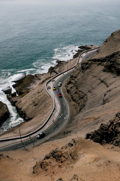 波状の海の岩の多い海岸の上のアスファルト道路