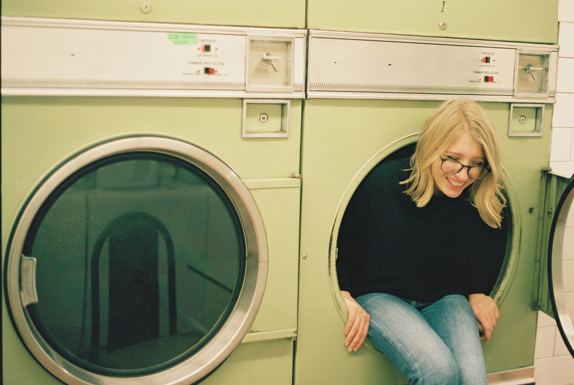Cheerful woman sitting in laundry machine