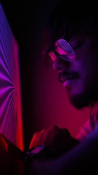 A close-up portrait of a young man illuminated by vibrant neon lights, creating a dramatic effect.