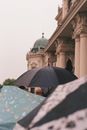 在多雨的环境中，优雅的建筑细节与雨伞共同捕捉了经典而喜怒无常的气氛