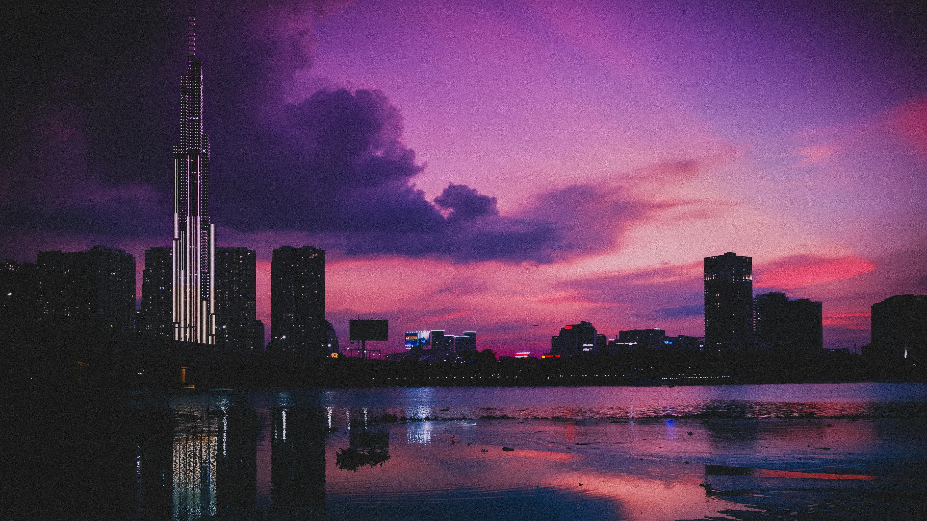 日落时分，当代摩天大楼的倒影映在城市河流中，天空多云却明亮