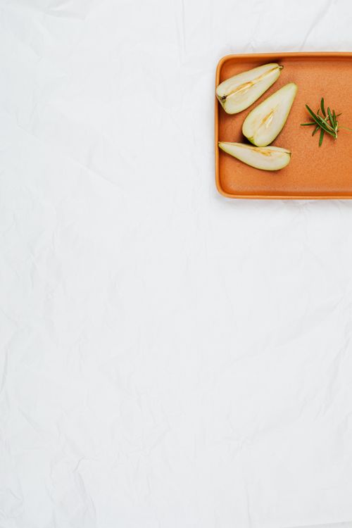 Free Minimalist flat lay of sliced pears and herbs on an orange tray with white background. Stock Photo