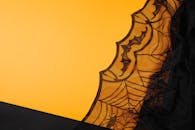 在充满活力的黄色背景下，一个类似蜘蛛网的黑色花边图案，唤起了万圣节主题