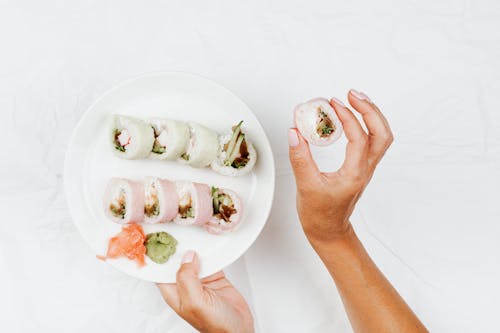 Flatlay Photo of a Person Holding a Delicious Makizushi