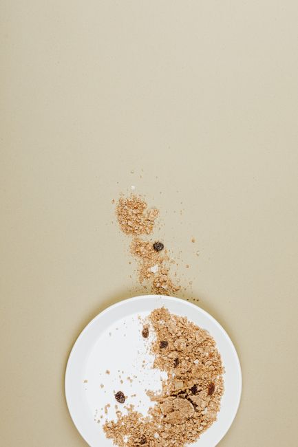 A large bowl of Rice Chex cereal coated in chocolate and peanut butter, dusted heavily with powdered sugar, with a wooden spoon resting in the bowl.