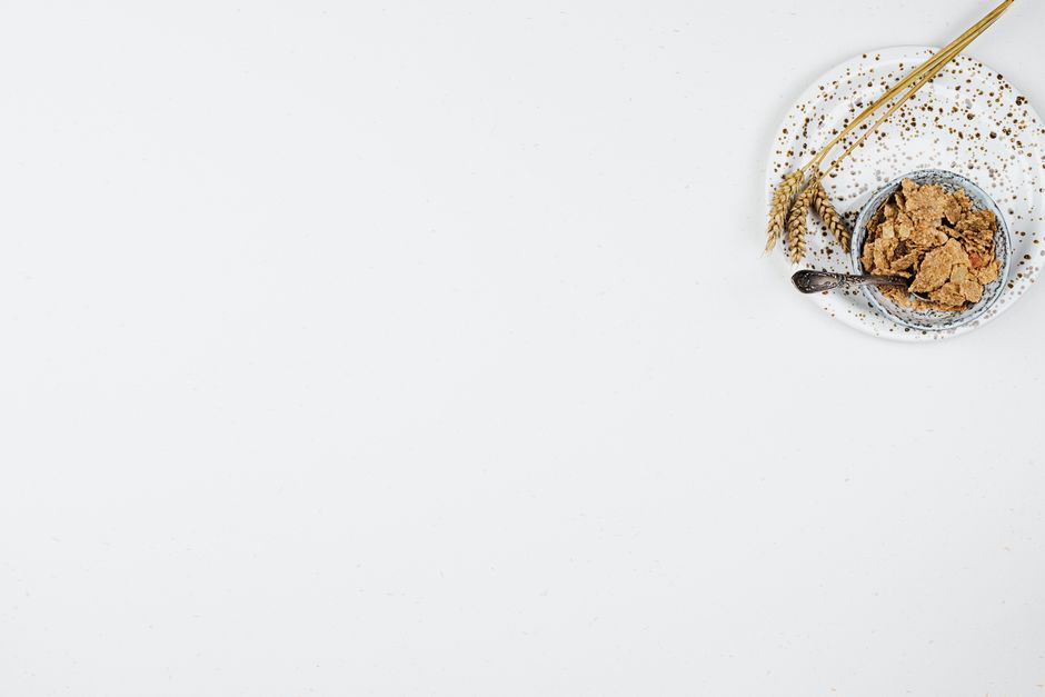 Minimalist style cereal bowl with wheat on a speckled plate, emphasizing breakfast simplicity.
