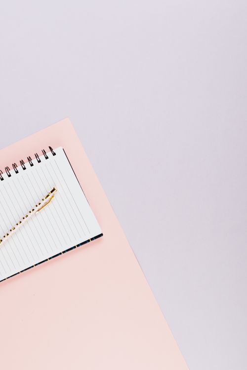 Free Elegant flat lay of spiral notebook and pen on a pink surface, perfect for creative projects. Stock Photo