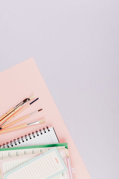 Free Top view of spiral notebooks and art brushes on pastel background, perfect for creative projects. Stock Photo