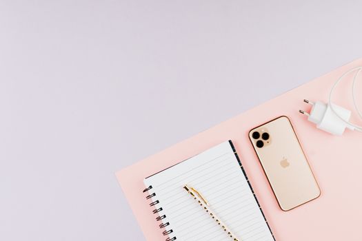 Flat lay image featuring a smartphone, notebook, and pen on a pink surface, ideal for modern technology themes.