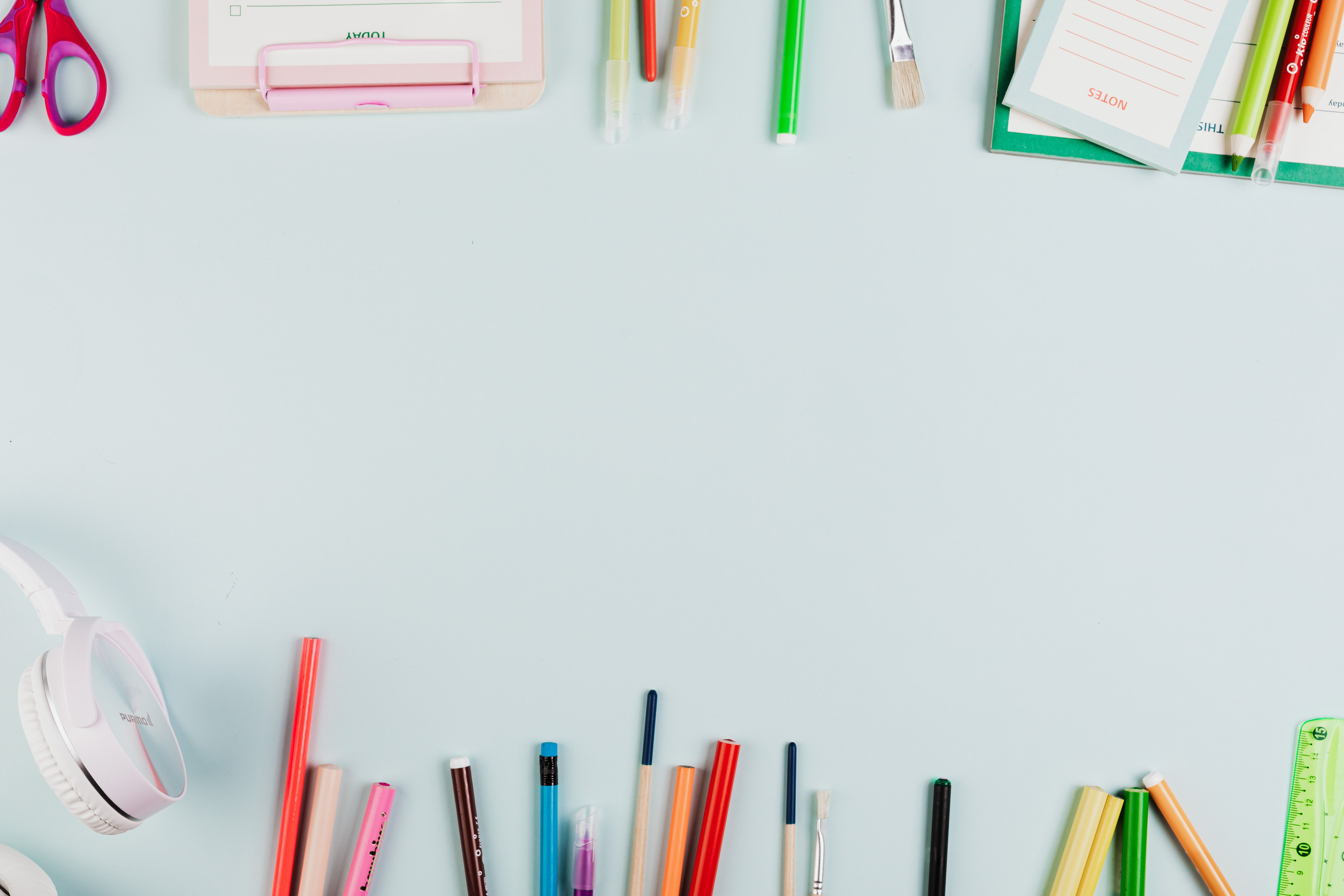 A vibrant flat lay of stationery items with ample copy space on a pastel surface.