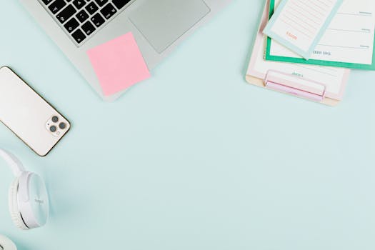 A clean, organized workspace featuring a laptop, smartphone, stationery, and headphones. Ideal for business themes.