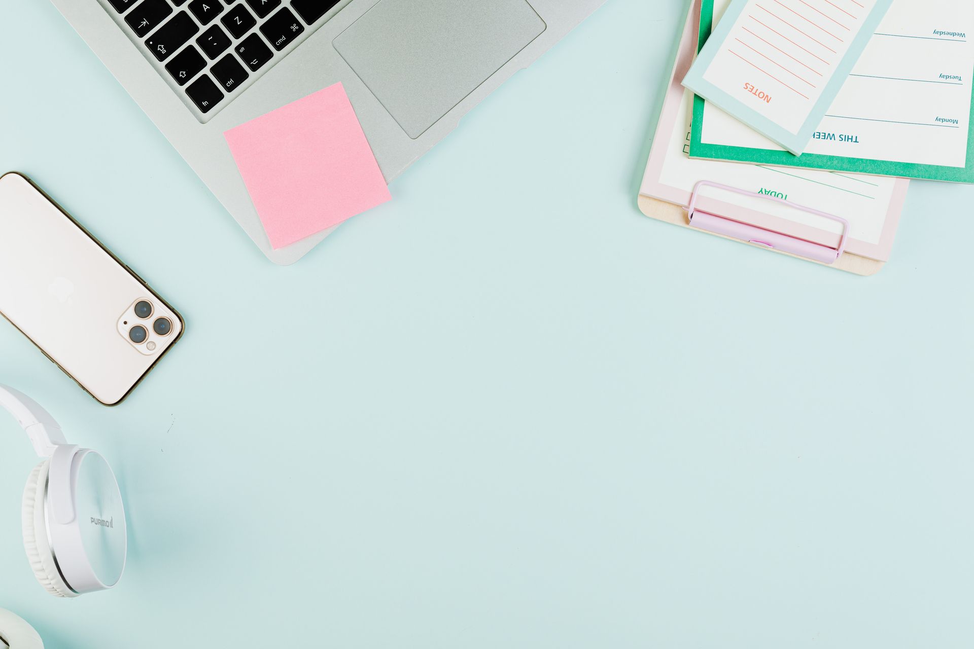 A clean, organized workspace featuring a laptop, smartphone, stationery, and headphones. Ideal for business themes.