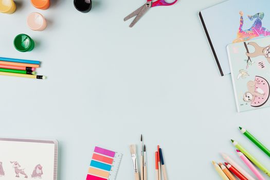 Top-view flat lay of art supplies on a pastel surface with ample copy space.