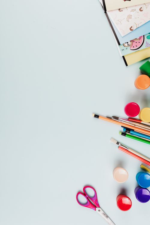 Free Flat lay of colorful art supplies including paints, pencils, and scissors on a light blue background. Stock Photo