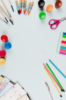 Flat lay of colorful art supplies on a light background with ample copy space.