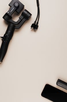 Flat lay of a gimbal, smartphone, and cables on a neutral surface. Perfect for tech-related content.