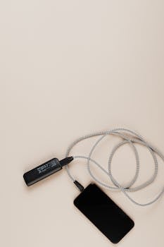 Overhead shot of a smartphone charging with a power bank on a plain background.