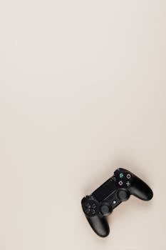 Black PlayStation controller on a neutral background with ample copy space.