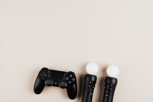 Black gaming controllers arranged on a light background with ample copy space.