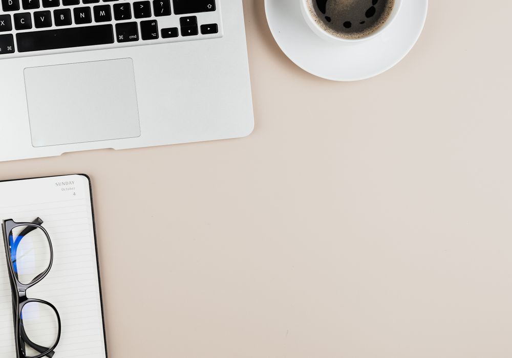 Tidy desk with laptop, notebook and coffee