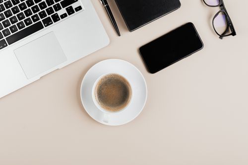 Free Flat lay of a modern workspace with coffee, laptop, and gadgets on a white background. Stock Photo