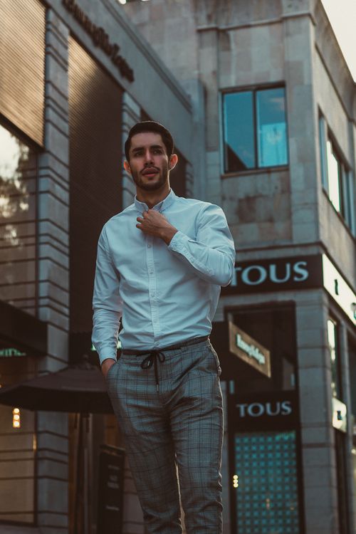 A Man in Long Sleeves Shirt and Plaid Pants Standing on the Street ...