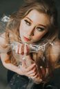 From above of charming female with blond hair and transparent package in hand near chin looking away in dreams inside