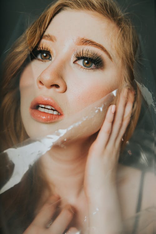 Woman with plastic wrap near face