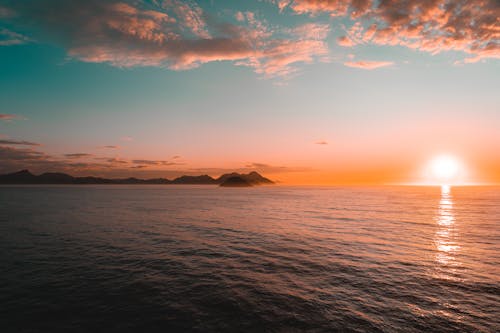 Silhouette of Mountains Near Body of Water during Sunset