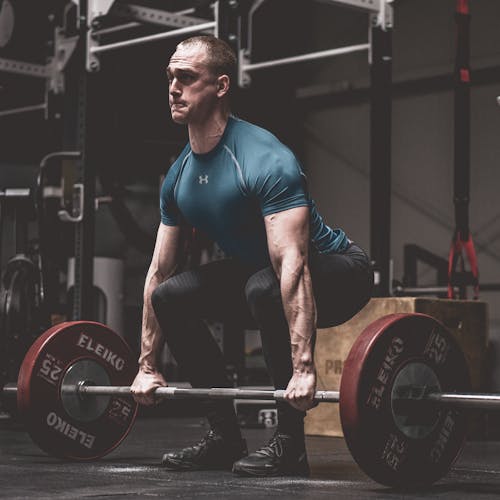 Free Man in Blue Shirt Lifting a Barbell Stock Photo
