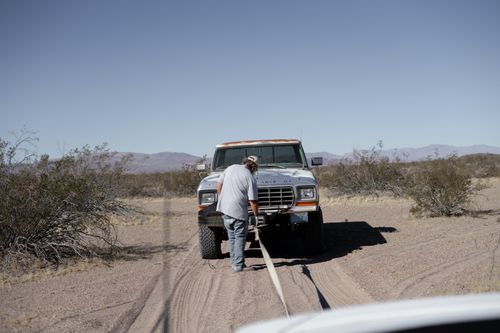 Free Man assisting stranded pickup truck in arid desert setting. Stock Photo