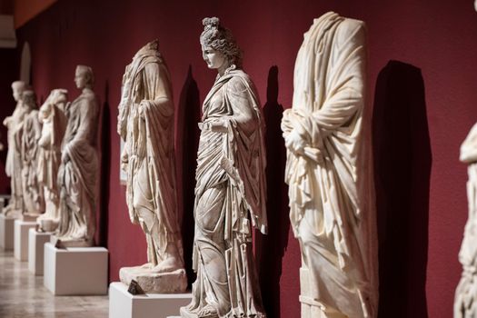 Headless Statues and a Statue of a Woman Against a Red Wall