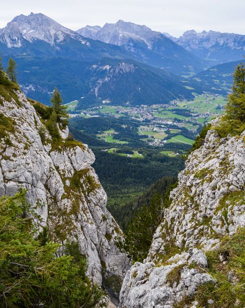 Free Frome above of rough cliffs covered with moss and firs near meadows and thick forests surrounded with snowy peaks and hills Stock Photo