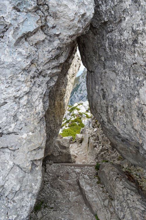 Old rocky cave near green mountains on sunny clear day in wild nature