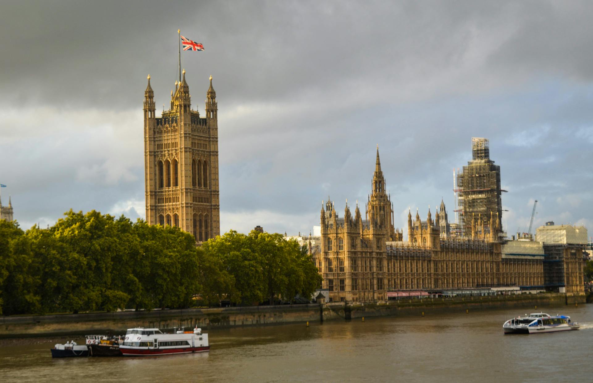 The Westminster Palace on green embankment of the River Thames