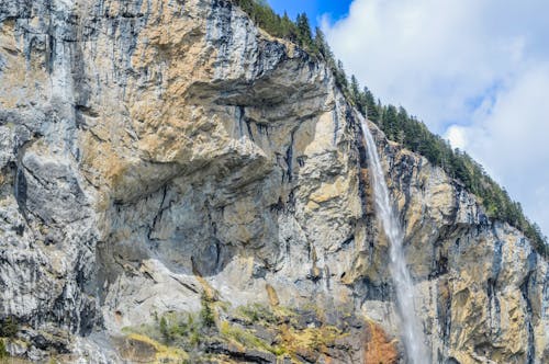 Free Rough mountain with fast waterfall under sky Stock Photo