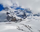 Mountainside covered in snow in clouds
