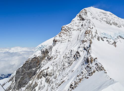 Spectacular view of peak with slopes covered in snow against clear blue sky