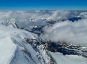 From above top of snowy mountain cliff and majestic clouds over mountainous valley at daytime
