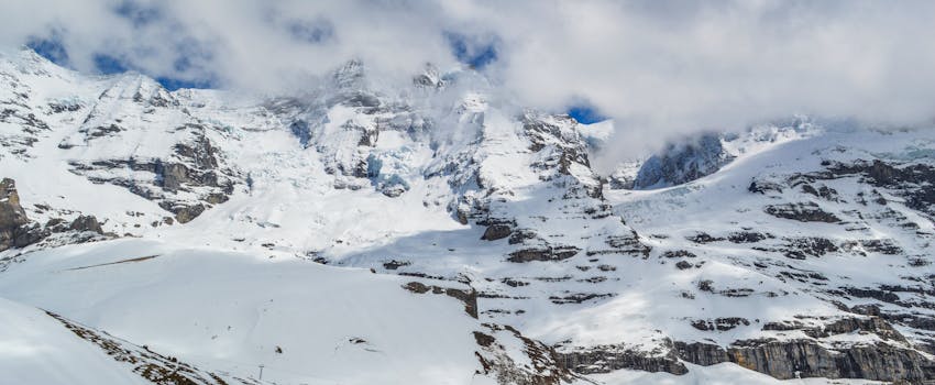 Breathtaking snow-capped mountains under a cloudy sky capturing a serene winter landscape.