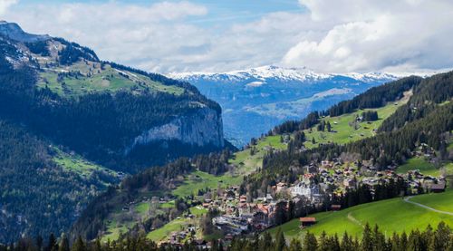 Free Magnificent landscape of mountainous valley with small settlement and lush green coniferous woods against cloudy sky in Lauterbrunnen Stock Photo