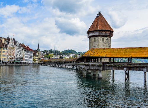 Stone construction of Kapellbrucke bridge with chapel tower in calm river in city of Lucerne
