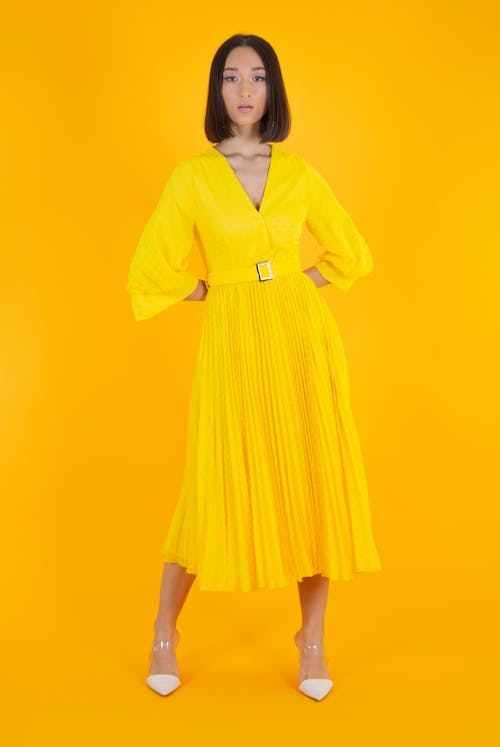 Gratis lagerfoto af gul baggrund, gul kjole, hænder bagud