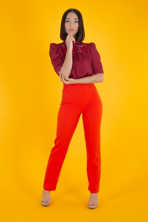 Free Stylish woman in maroon blouse and red pants posing confidently on a vibrant yellow backdrop. Stock Photo