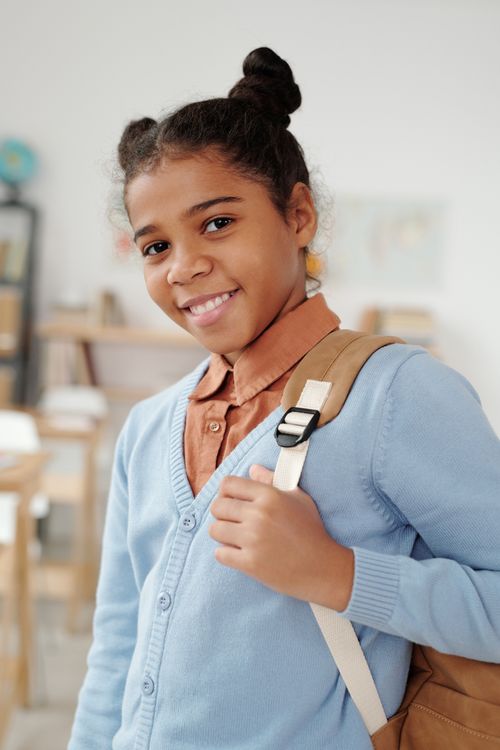 Free Happy girl with backpack in classroom, ready for school day. Stock Photo