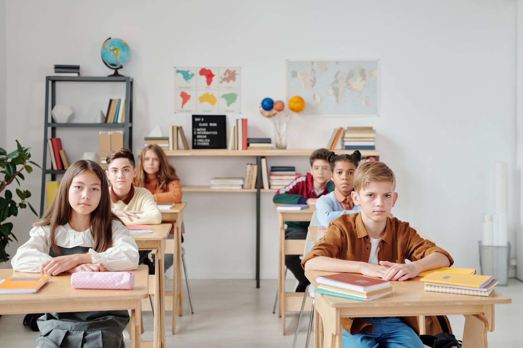 Crianças sentadas enfileiradas em sala de aula tradicional
